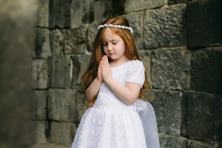 Modląca się dziewczynka w sukience na 1 komunii świętej