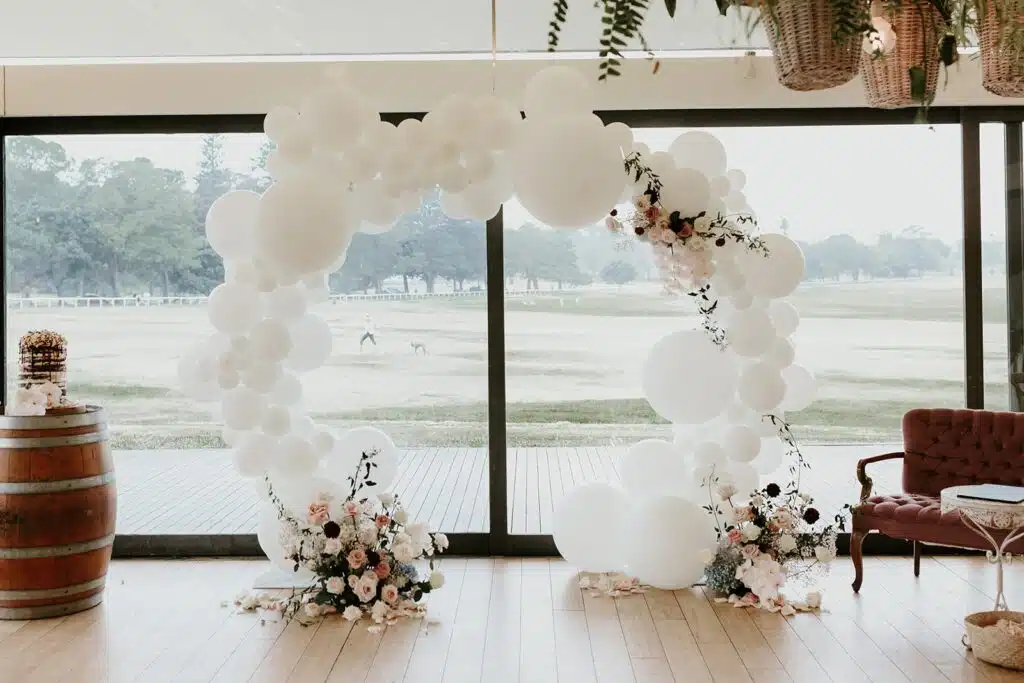 Złote koło z białymi balonami oraz kwiatami na uroczystości weselnej